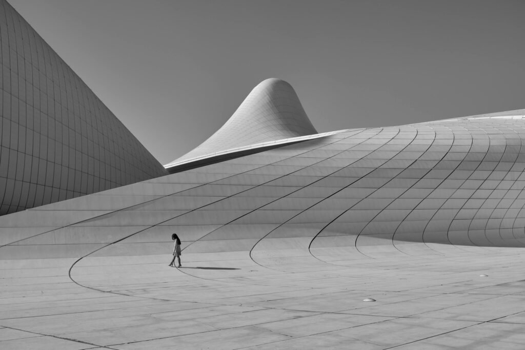 Black and white image of the futuristic Heydar Aliyev Center in Baku with a lone woman walking.