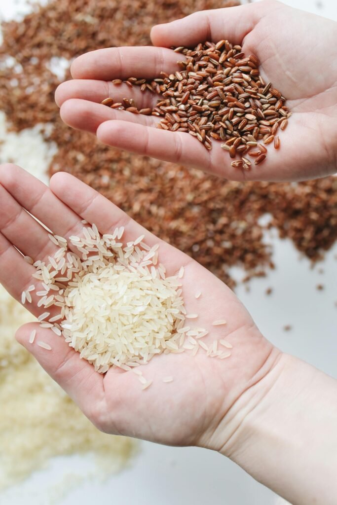 Hands holding red and white rice varieties, showcasing raw grains.